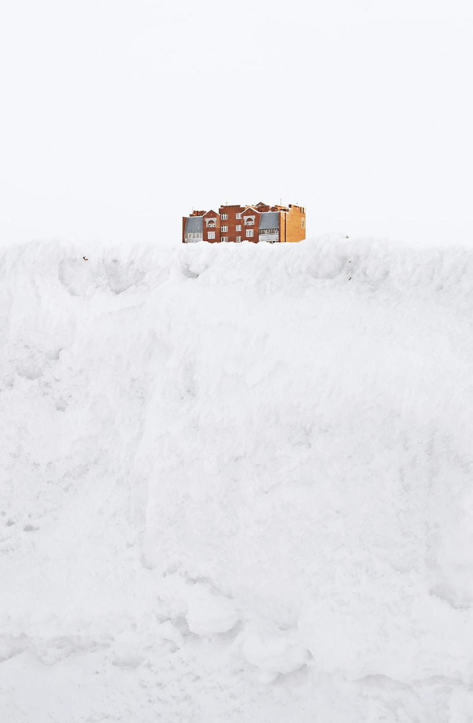 Snow-covered modern building against mountain backdrop